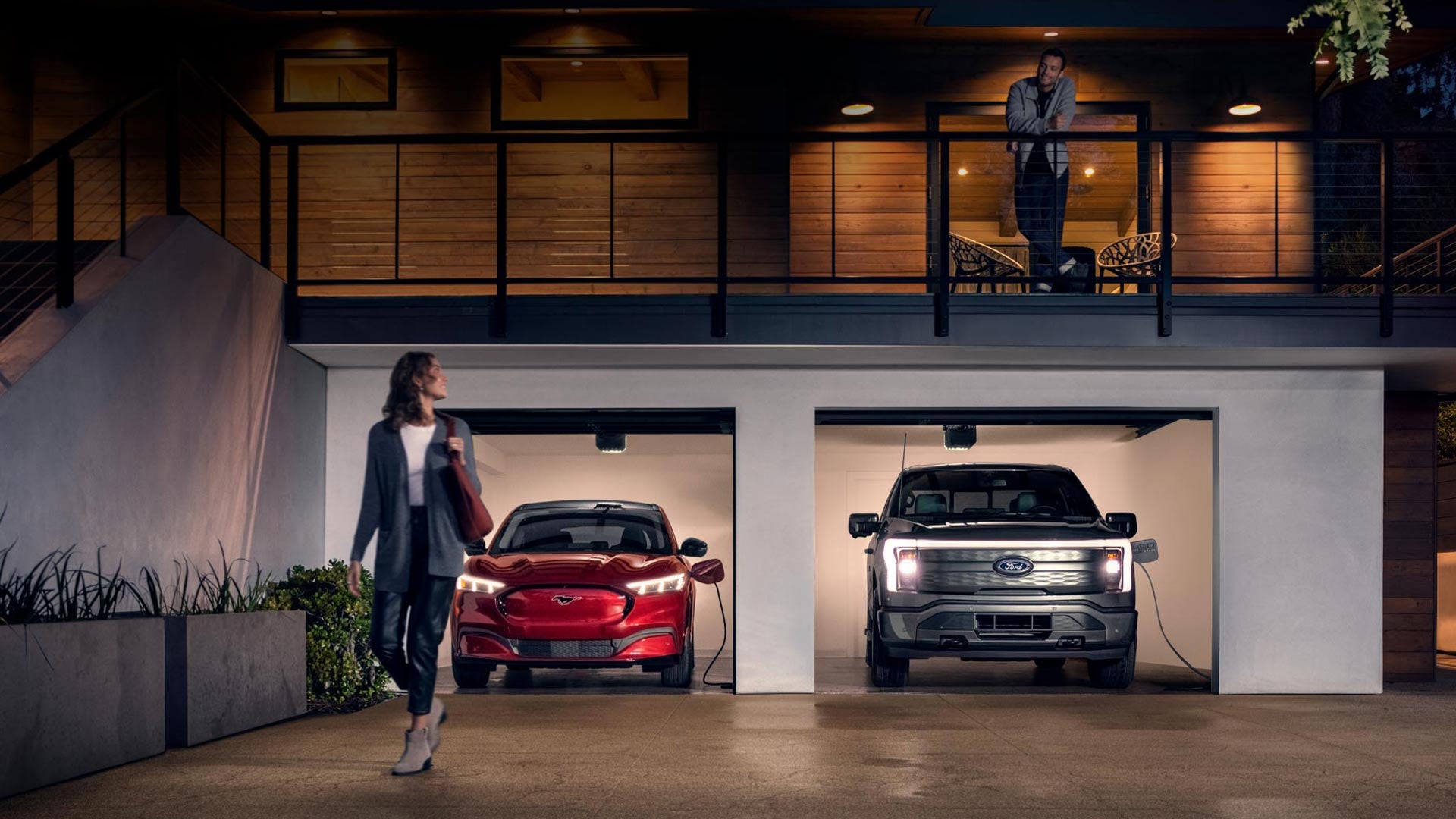 Woman walking out from home garage with a 2024 Mustang® Mach-E and Ford Lightning® truck in plugged-in and charging | Kisselback Ford in Saint Cloud FL